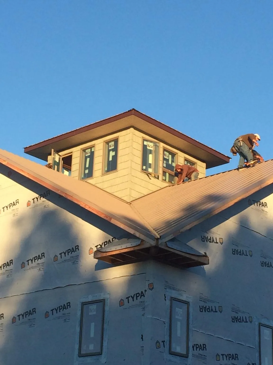 Roofers working around a rooftop cupola on a new metal roof at sunset — Roof Waterproofing in Aurora by Roofing Brothers